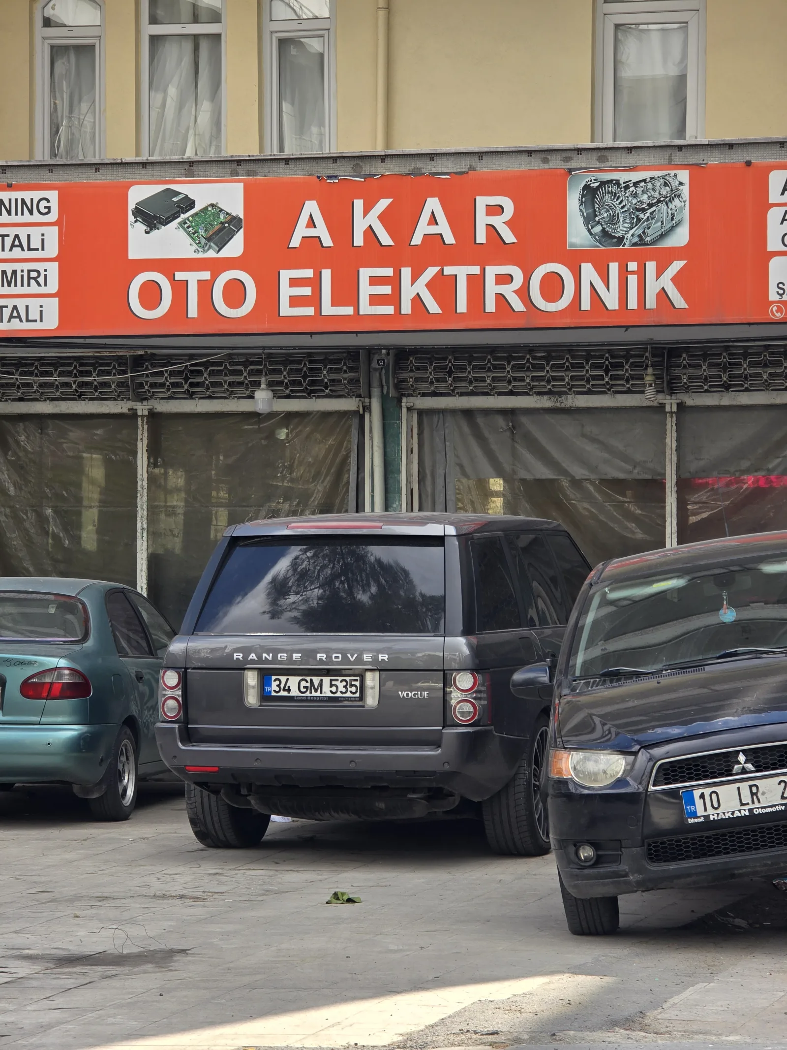 Sokağa bakan dikey Akar Oto Elektronik tabelası ve hizmet simgeleri