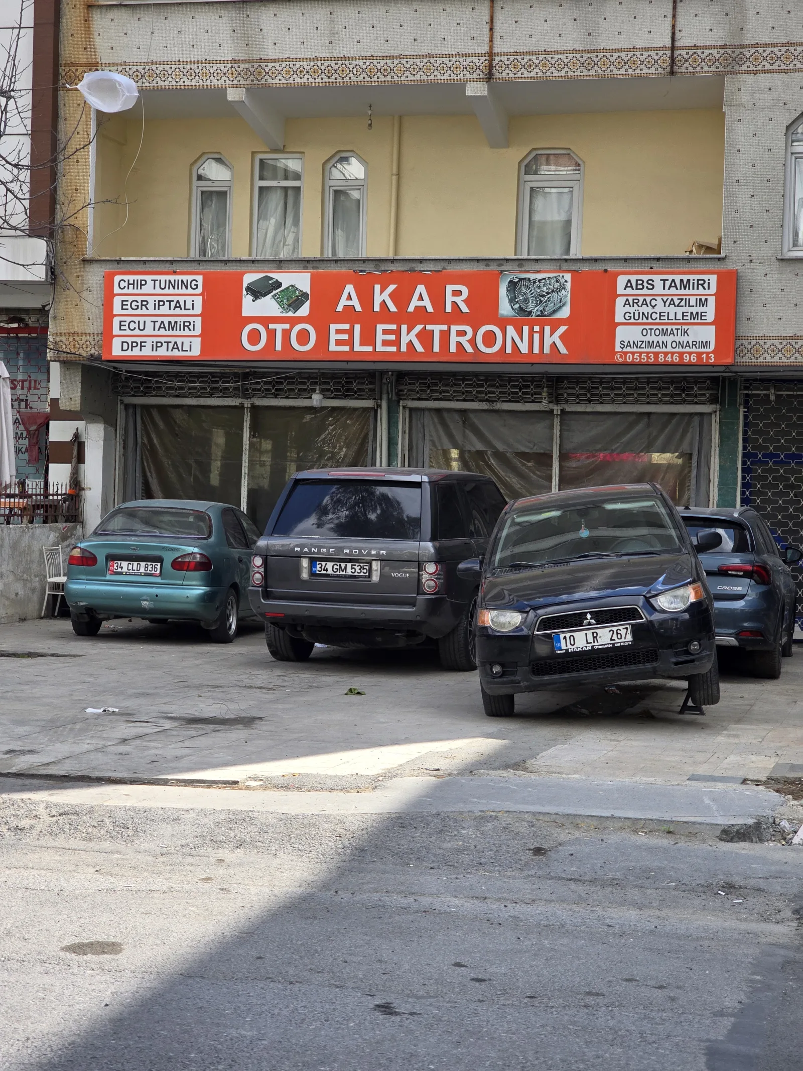 Atölye önünde sıralanmış araçlar ve yanlarında yükselen tabela