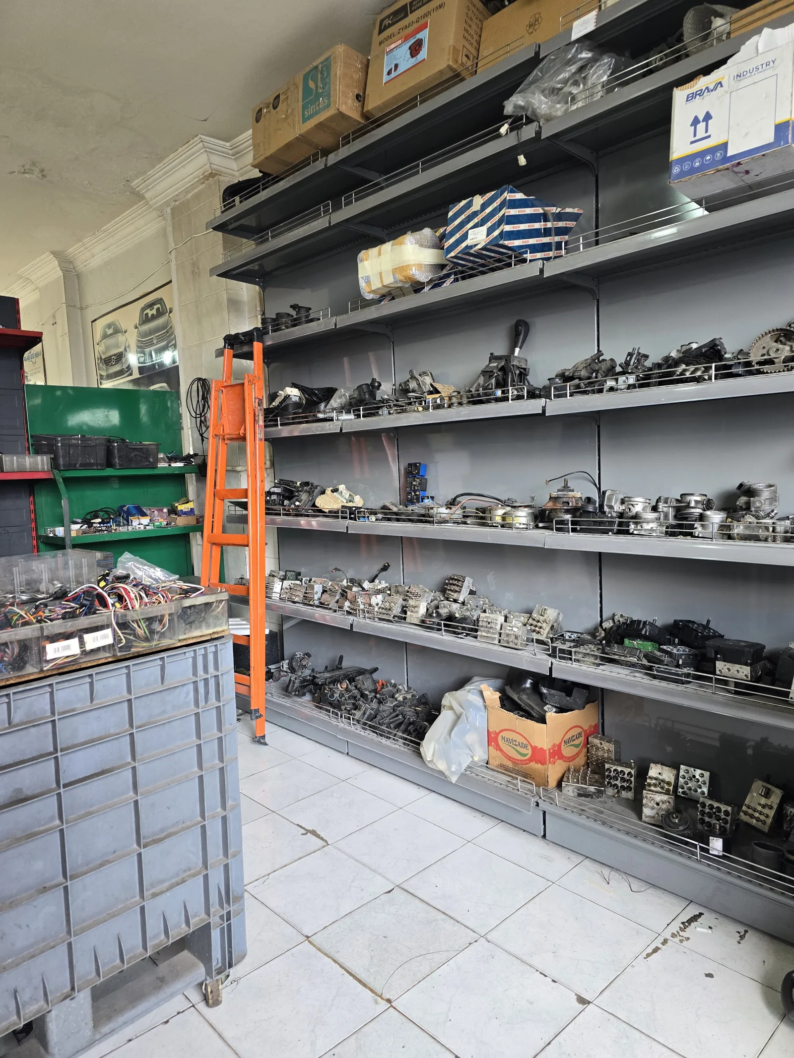 Uzun raf sıralarında etiketlenmiş hâlde bekleyen araç elektronik üniteleri