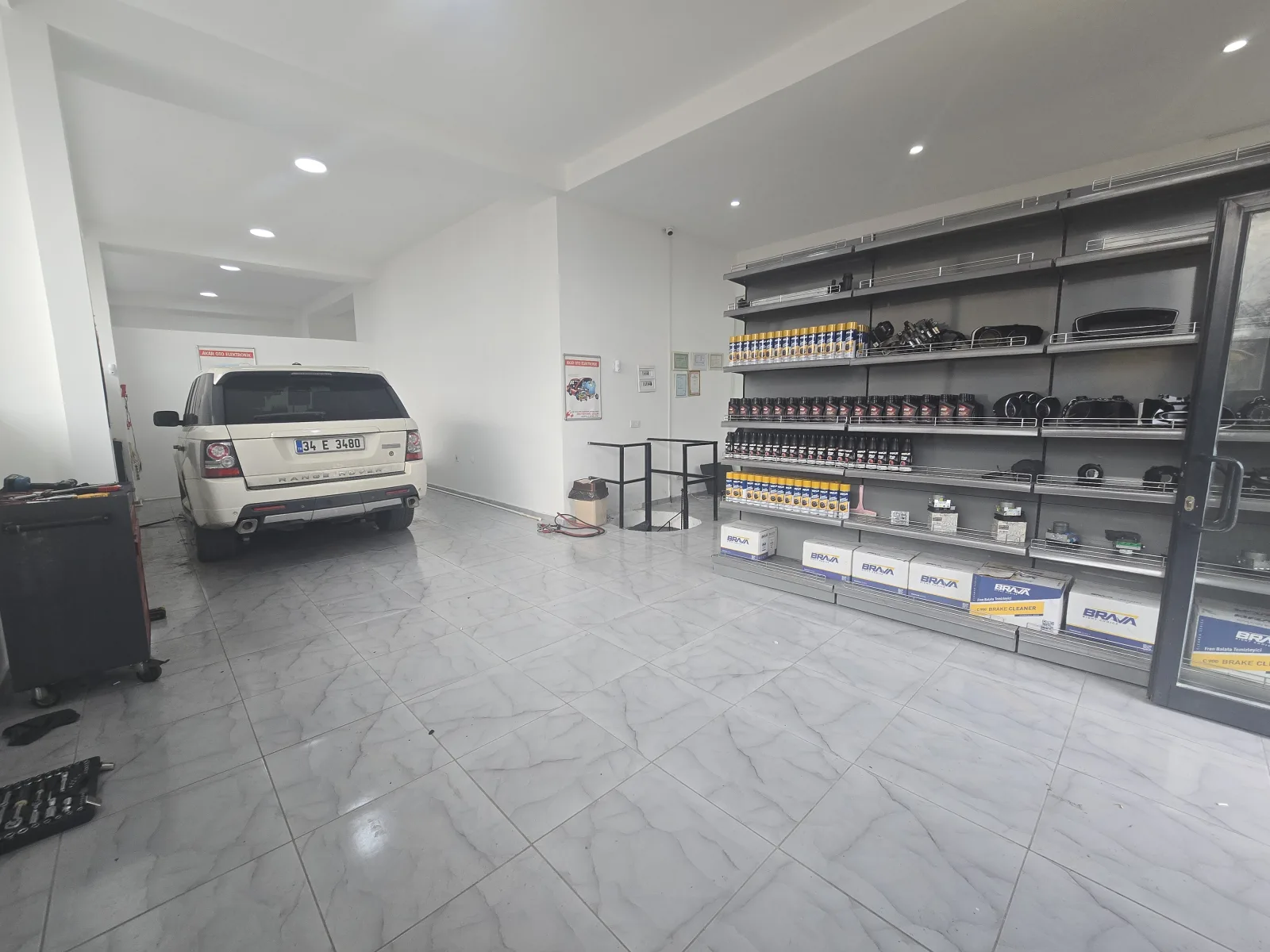 Yeni dükkânın geniş servis alanı ve duvar boyunca uzanan parça rafları