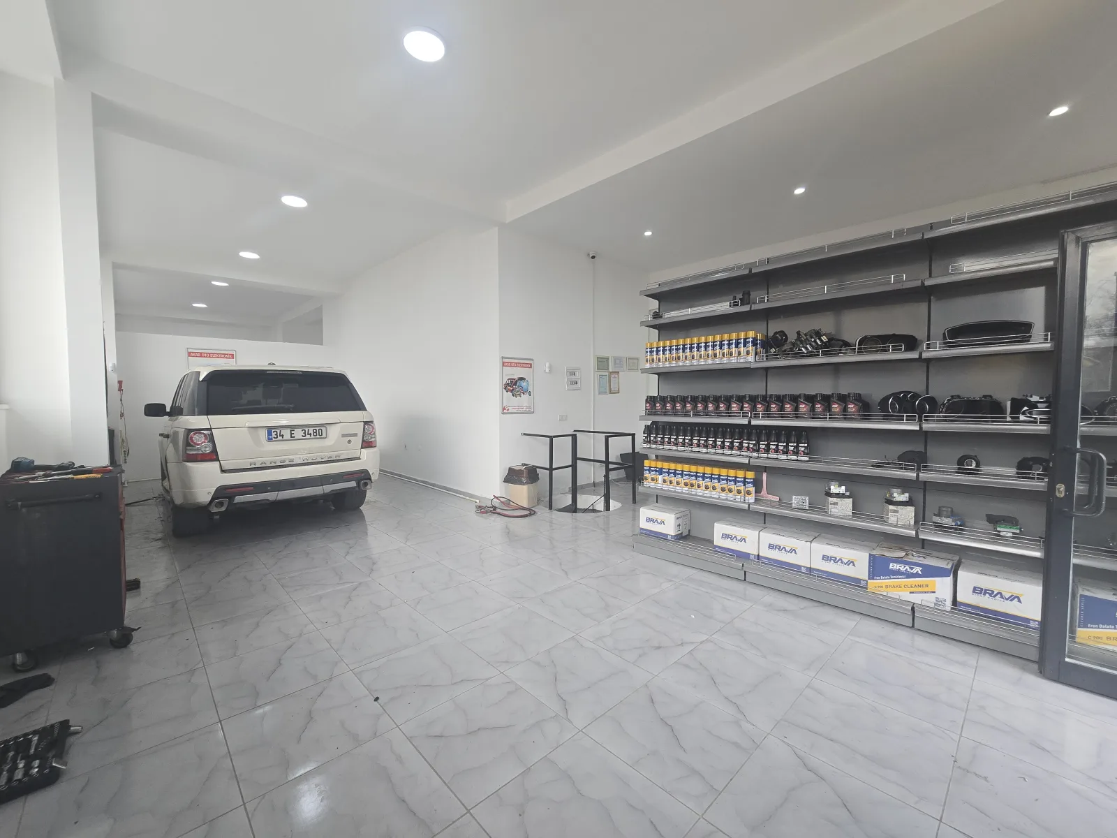 Servis alanındaki araç ve arkasındaki düzenli yedek parça rafları