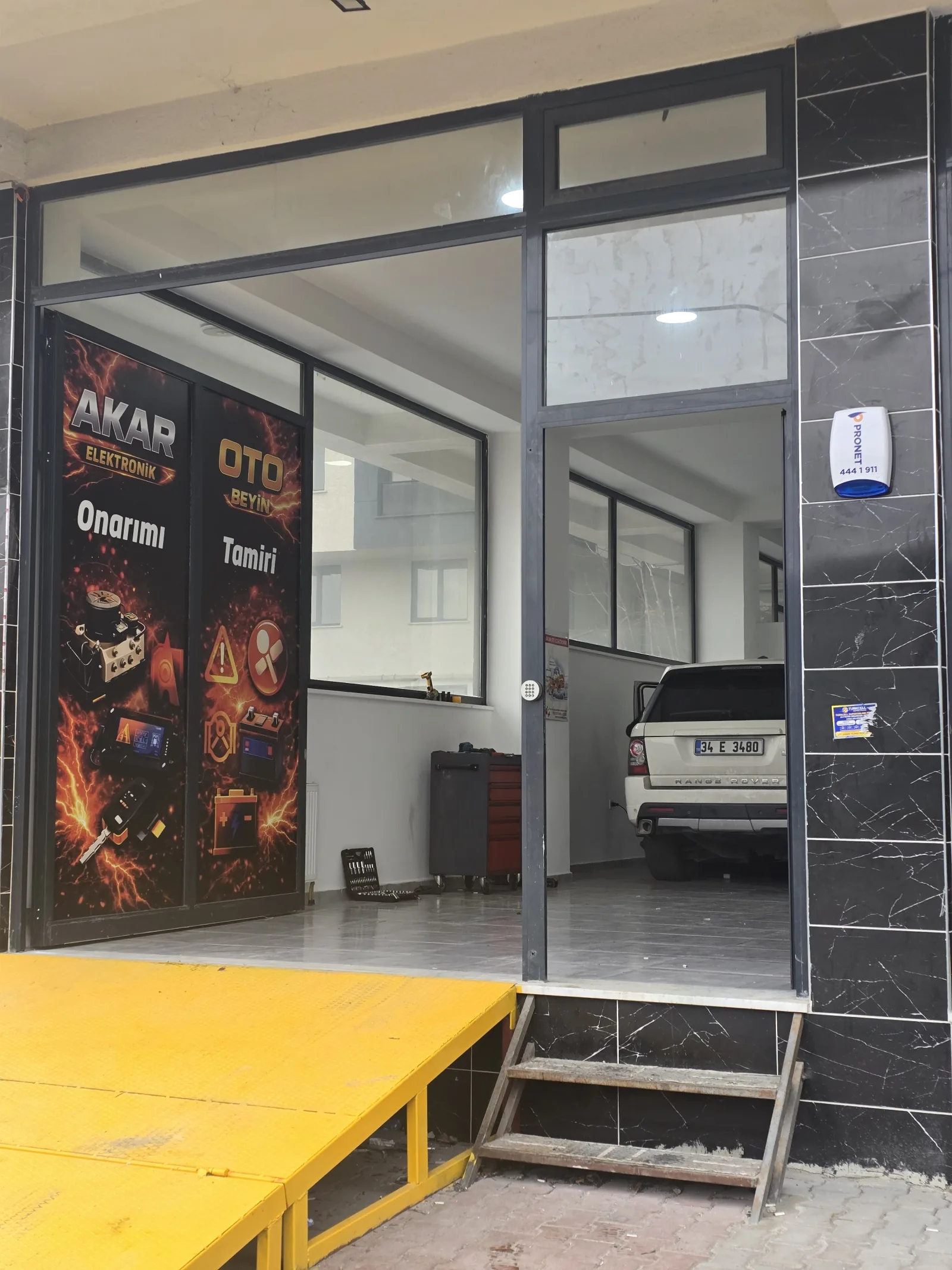 Yeni dükkânın cam kapısındaki Akar Elektronik oto onarım görseli